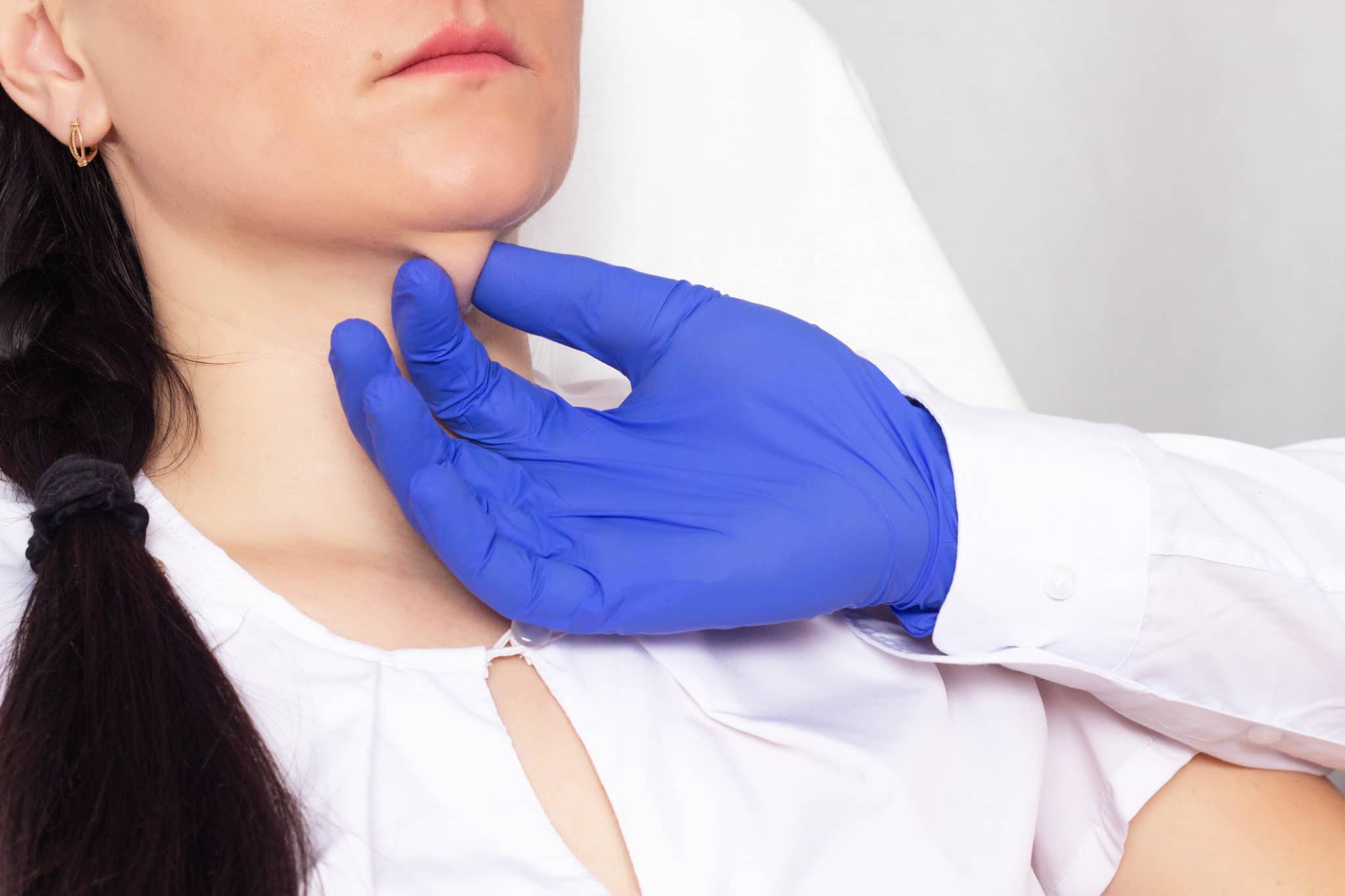 Doctor cosmetologist checks the skin for elasticity on a double chin in a girl