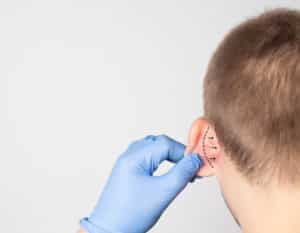 A plastic surgeon doctor examines a male patient s ear for an otoplasty operation.